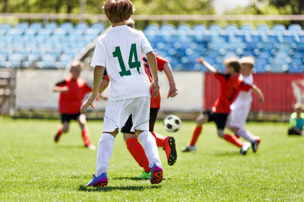 Дети играют в футбол в школе. Летний футбольный турнир для юношеских команд. Мальчики бегут быстро и быстро за мячом на грасс-пит