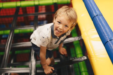 Neşeli Çocuk oyun alanında eğleniyor. İlkokul çocuğu oyun merkezi inşaatında oynuyor. Çocuklar için Lunapark Cazibesi