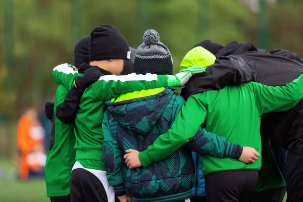 冬時間のスポーツトーナメントゲーム中に若いコーチとチームのスポーツキッズ 冬の帽子とジャケットの子供たちがチームサークルに立って — ストック写真