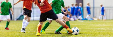 Yeşil ve Kırmızı Takımdaki Çocuklar Çimenlerde Futbol Oynuyor. Çocuklar için Spor Eğitimi. Okul çocukları futbol topunu tekmeliyor. Genç Çocuklar için Spor Açık Etkinliği