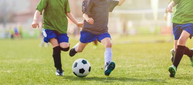 Çocuklar Futbol Turnuvası. Çocuklar Futbol Maçı Düellosunda yarışıyor. Topa vurma anı. Genç Tekmeleyen Top. Okul çocukları Çimen Sahasında Klasik Futbol Topu koşuyor