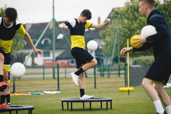 Coach Coaching Youth Football Team. Players Kicking Balls and Jumping on Fitness Trampoline. Balance Training in Youth Soccer Club