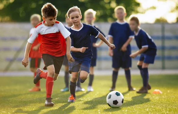 サッカーのトレーニングゲームをしている若い男の子 ジュニアサッカー練習試合は 決闘で走る選手とサッカーボールを蹴る選手の間で行われる ユースサッカーチーム間のトレーニングとサッカー試合 — ストック写真