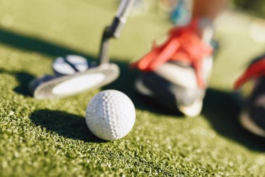 Çocuklar mini golf oynar. Mini golf ve beyaz golf topu ile snickers içinde oyuncunun yakın plan görüntüsü