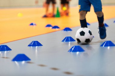 Futsal Ball 'lu Futbol Elbiseli Çocuk, Dribbling Drill' de. Koç ile iç saha futbol antrenmanındaki çocuk. Çocuk tahta zeminde Futsal oynuyor. Koç Antrenörüyle Futsal Okul Çalışması
