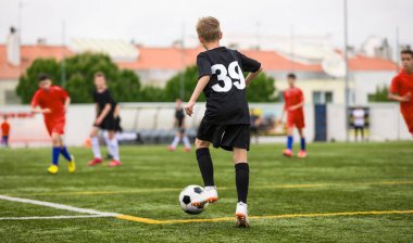 Genç çocuk maç boyunca futbol topuyla koşuyor. Okul takımları arasında Avrupa futbol maçı