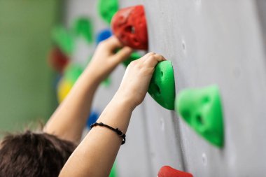 Kapalı alan tırmanma duvarındaki okul çocuğu. Çocuk kaya duvarında eğleniyor. Çocuk tırmanma dersinde öğreniyor. Spor, sağlıklı yaşam tarzı. Gençlik yaz kampına tırmanıyor.