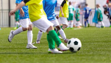 Karşıt takımlarda futbolcu çocuklar topa vuruyor. Genç Futbolcular Düelloda Koşuyor ve Futbol Turnuvası Maçı Oynuyor. Genç sporcular için spor müsabakası. Okul Eğitim Sahası Arkaplanda 