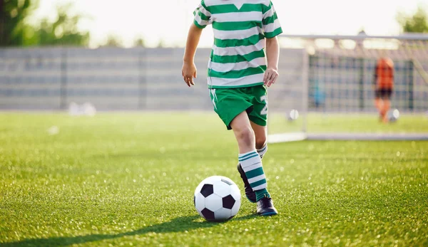 Futbolcu Koşan Top Arkaplanı. Düşük açılı futbol oyuncusunun Çimen Eğitim Alanında Tekmeleyen Top resmi. Çizgili Futbol formalı okul çocuğu.