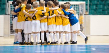Coach giving young soccer futsal team advices before soccer tournament game stars. Indoor football soccer match for children. Youth soccer team. Football match for children. Coach briefing