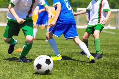 Boys play soccer. Teenagers at school playing soccer in sports field. Children kicking soccer game outdoors. Young male footballers running in red and blue sports uniforms