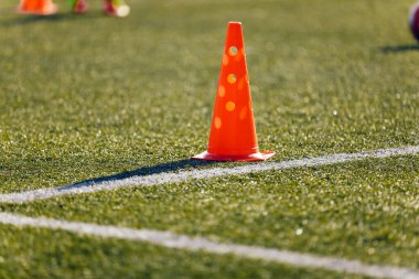 Football Grass Antrenman Sahası. Grass Pitch 'te futbol ekipmanı. Kırmızı Eğitim Konisi. Arkaplanda Çalışan Oyuncu