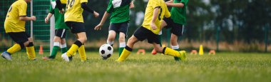 Çocuklar dışarıda futbol oynarlar. Çocuklar futbol maçında gol atıyorlar. Çocuklar topa vuruyor. Forma ve kramponlarla koşan çocuklar. Okul futbol kulübü. Genç bir oyuncu için spor eğitimi