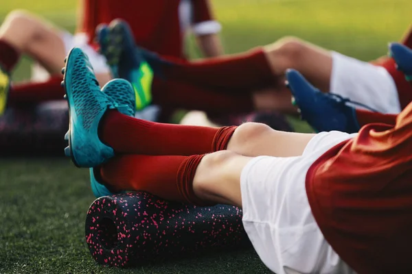 Soccer Football Players in a Team on Fitness Workout to Relieve Muscle Tightness, Soreness, and Inflammation. Group of Young Athletes on Stretching Outdoor Session with Foam Rollers and Mats