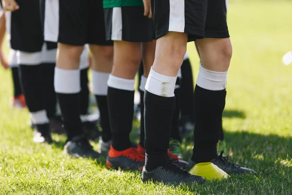 Sports team standing on grass venue. Closeup picture of soccer player\'s feet. Footballers standing in a row on training