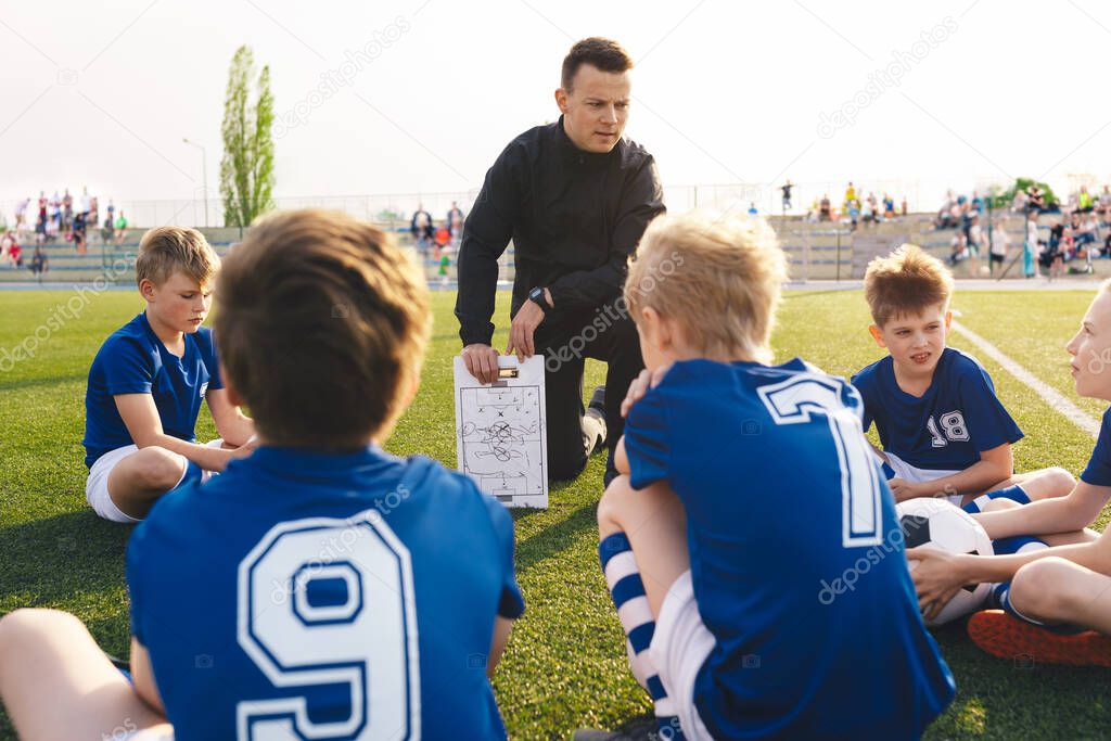 Coach explains a game strategy using board. Young coach teaching kids on football field. Football coach coaching children. Soccer football training session for children. Football tactic educatio