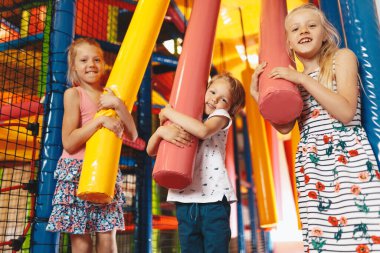 Oyun merkezinde birlikte oynayan heyecanlı çocuklar. Mutlu kardeşler lunaparkta birlikte oynuyorlar. Bir alışveriş merkezinin renkli oyun bahçesinde oynayan sevimli okul çocukları.