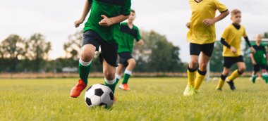Koşan ve futbol oynayan oyuncular arasındaki rekabet. Genç çocuklar futbol oynuyor. Çocuklar sporda eğleniyor. Mutlu çocuklar futbol maçında yarışıyor. Koşan futbolcular. Futbol okulu.