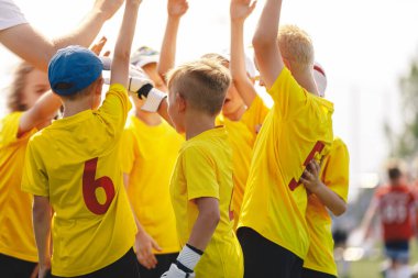 Sahada el ele tutuşan mutlu çocuklar spor takımı. Motive olmuş çocuklar spor takımı el kaldırıyor. Spor kampındaki çocuklar maçtan önce el ele tutuşuyorlar. Okul çağındaki çocuklar takımda. 