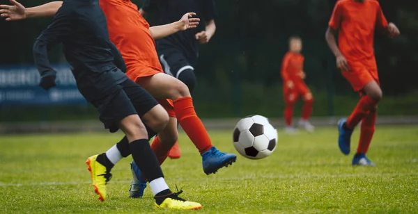Competition between players running and kicking football ball. Young boys playing soccer game. Kids having fun in sport. Happy kids compete in football game. Running soccer players. Football school