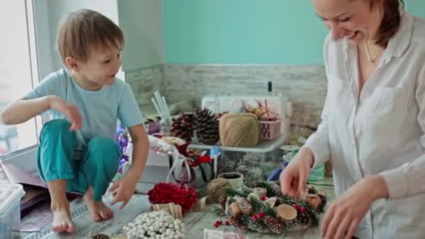 A girl and a child collect a Christmas wreath together. — Stock Video