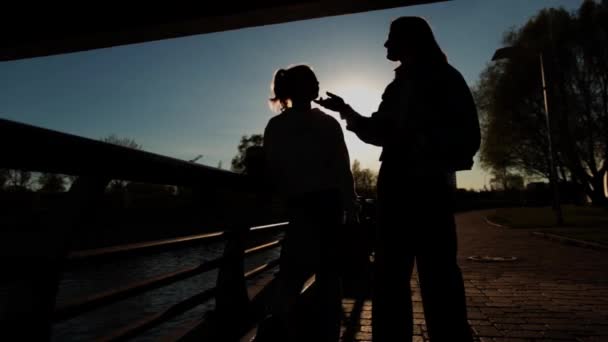 Moeder en dochter silhouetten onder de brug. — Stockvideo