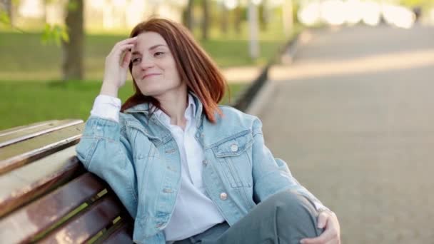 Mujer sentada en el banco en el parque — Vídeo de stock