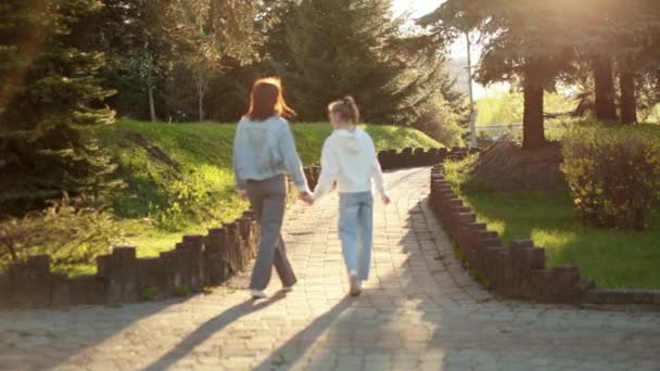 Matka a dcera se drží za ruce při procházce v parku — Stock video