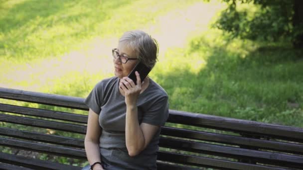 Glada kvinna pratar telefon i parken — Stockvideo