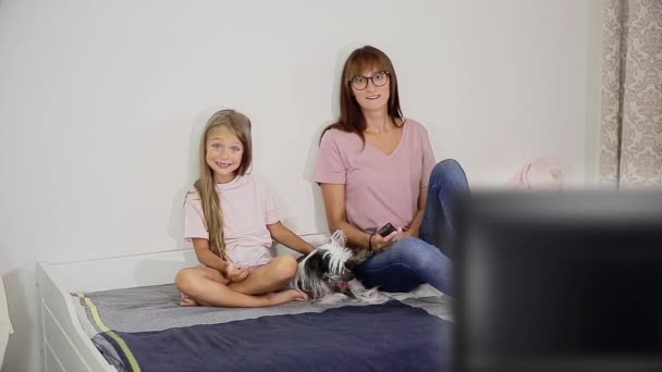 A woman with a child and a dog sitting on the bed watching tv — Stock Video