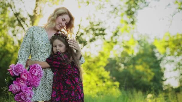 Молодая женщина и ребенок обнимаются в поле — стоковое видео