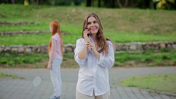 Ung kvinna pratar i telefon i parken — Stockvideo