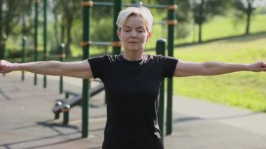 Yaşlı bir kadın oyun parkında ısınıyor..