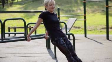 Yaşlı bir kadın oyun parkında ısınıyor..