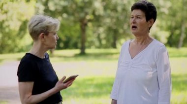 Parkta bekleyen neşeli yaşlı kadın çift.