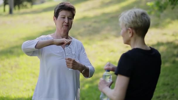 陽気な年配の女性が話し、水のボトルを保持 — ストック動画