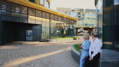 İş kadınları ofis binasının önünde konuşurken tartışıyor