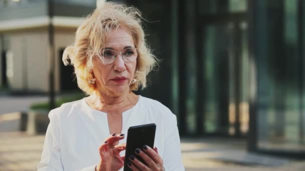 Usmívající se blond obchodnice držící digitální tablet před kancelářskou budovou — Stock video