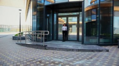 Cam bir çıkışın arka planında gülümseyen bir kız kağıt fırlatıyor.