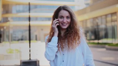 Kız şehirde sokakta telefonla konuşuyor ve cama yansıyor..