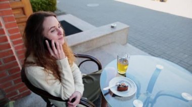 Kızım bir kafede oturup telefonla konuşuyor.