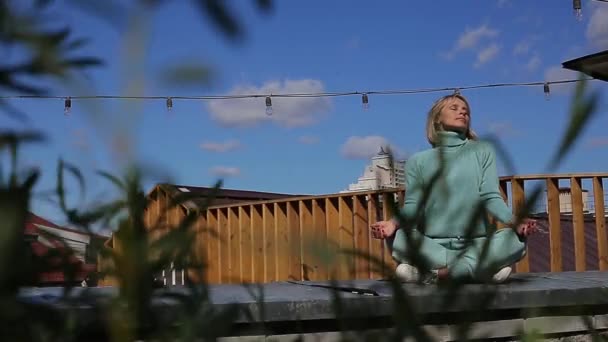 Sorrindo mulher adulta média com os olhos fechados meditando no telhado — Vídeo de Stock