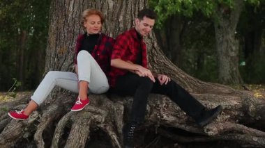 Erkek, ağacın altında otururken kadını öpüyor.