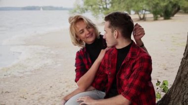 Kumsalda gülümseyen kız arkadaşı kucaklayan genç adam.