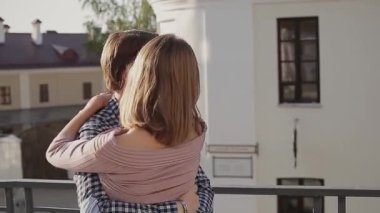 Gülümseyen erkek arkadaş kollarında kız arkadaşıyla yaya yolunda dikiliyor.