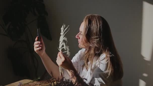 Женщина с папоротником делает селфи на мобильном телефоне дома — стоковое видео