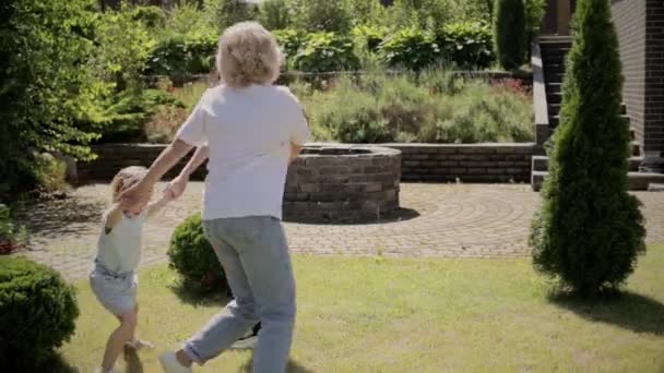 Abuela con dos nietas girando en el jardín — Vídeos de Stock