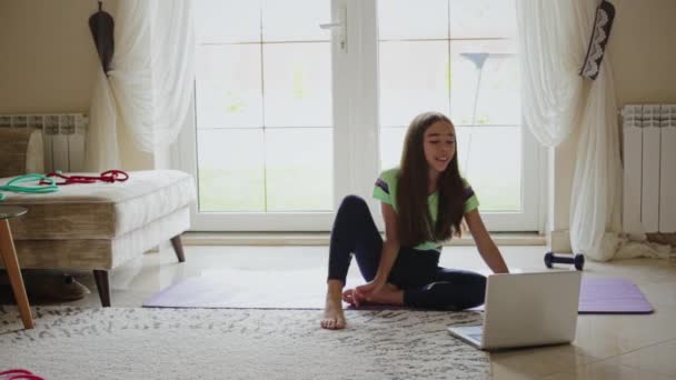 Dizüstü bilgisayarın önünde jimnastik yapan bir çocuk. — Stok video
