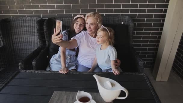 Gülümseyen büyükanne akıllı telefondaki torunlarıyla selfie çekiyor. — Stok video