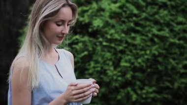 Güzel bir kız elinde fincanla sokakta duruyor.